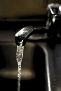 A kitchen faucet lit by sunlight above a sink.