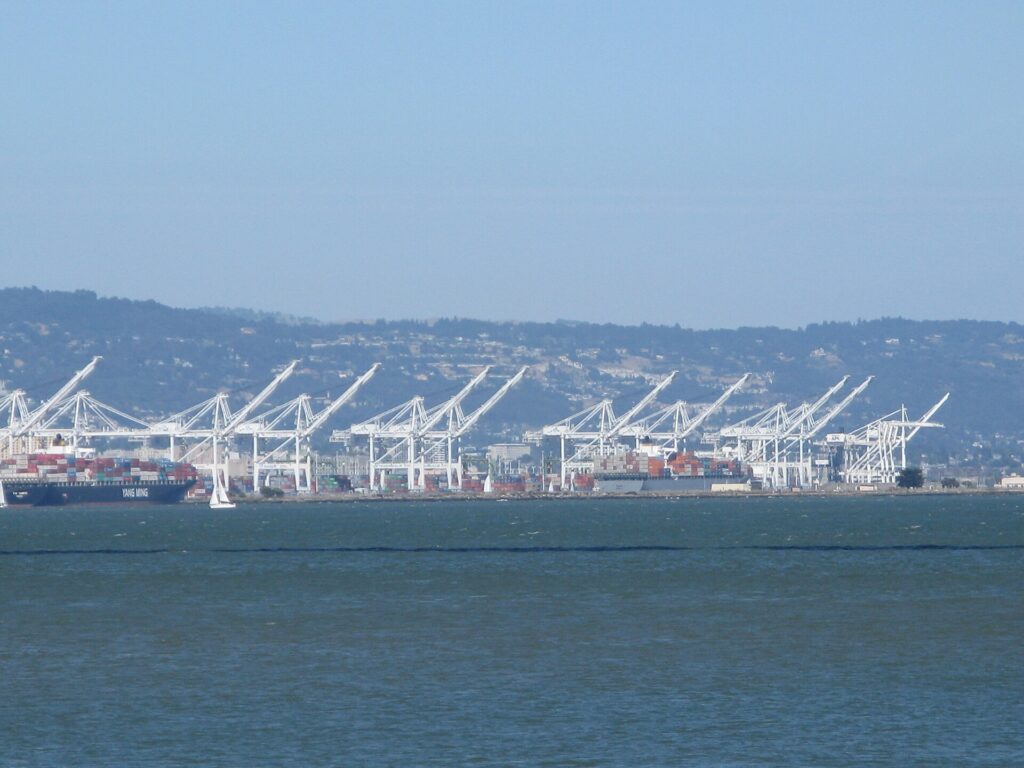 Automated cranes loading containers onto a ship in a large port at dusk.