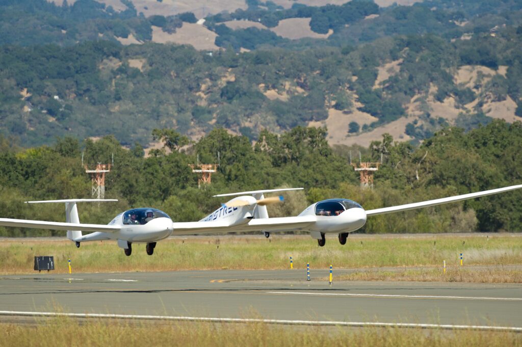 A small electric aircraft prototype parked on an airfield at sunset.
